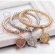 Three interconnected beaded bracelets in gold, silver, and rose gold tones, each with a dangling heart charm featuring a Tree of Life design.