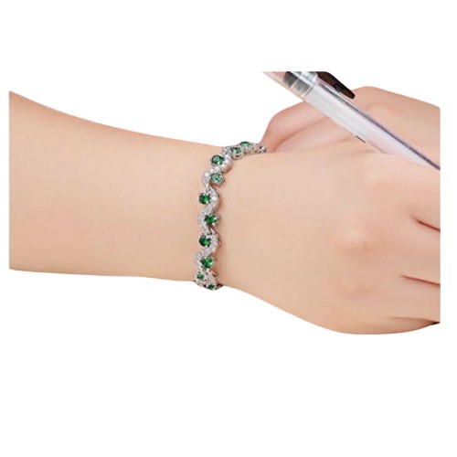 A beautiful silver bracelet with emerald green crystals and clear crystals set in a wavy pattern.